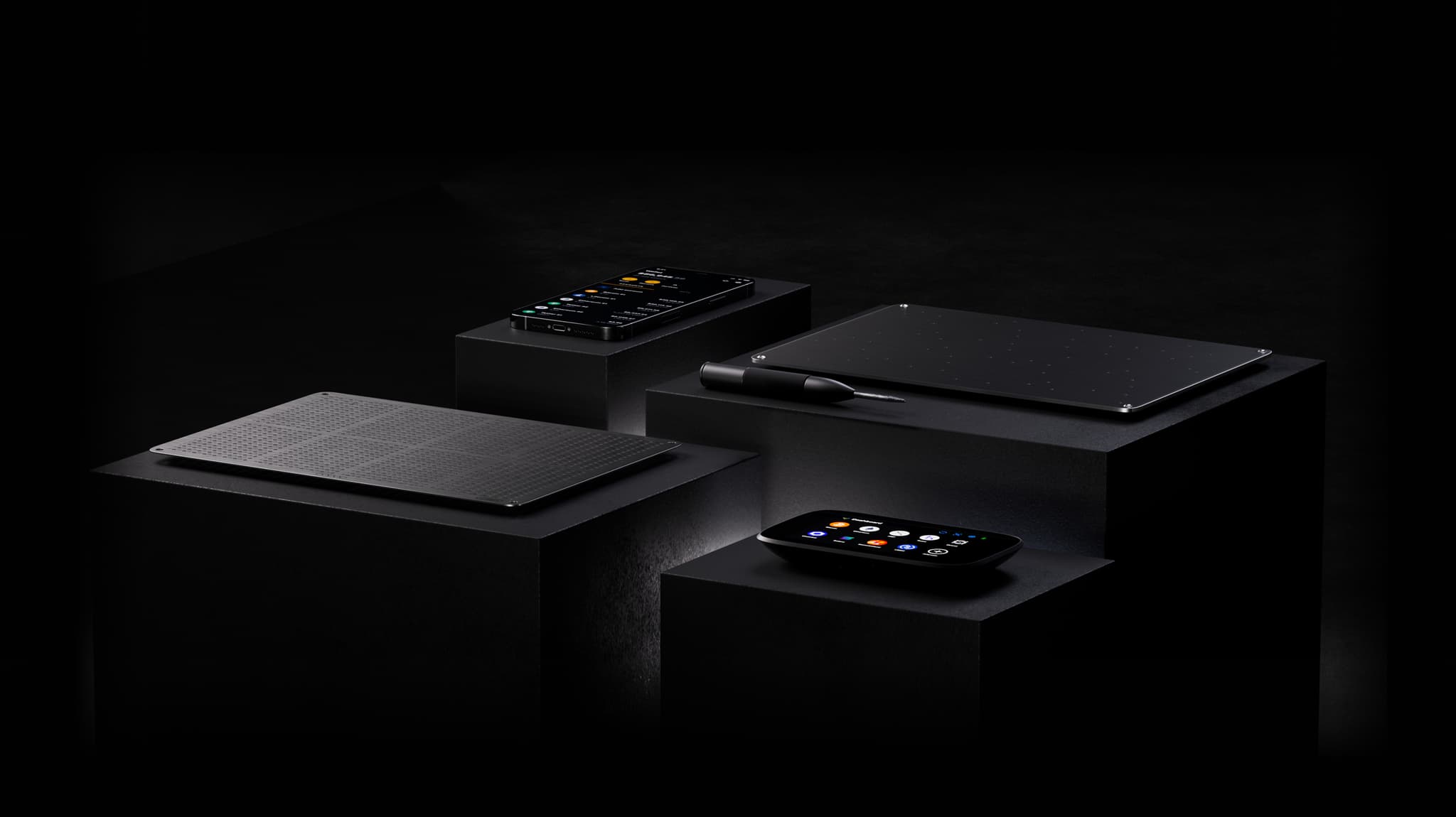 NGRAVE ZERO, LIQUID on a phone and GRAPHENE plates with punch tool displayed on black pedestals